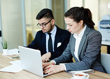 Busy co-workers Two business colleagues doing their work by desk in office