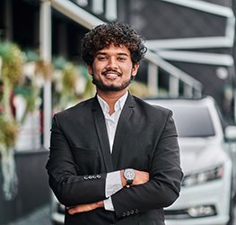 Indian businessman in the background of his white car.