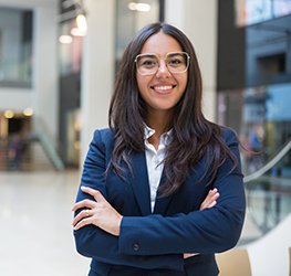 Young businesswoman smiling at camera. Portrait of cheerful Hispanic businesswoman in formal wear standing with crossed arms and looking at camera. Business concept